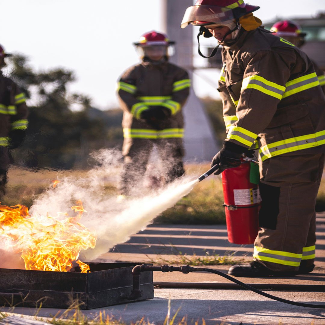 Fire safety professionals using a fire extinguisher during live fire training and emergency response demonstration